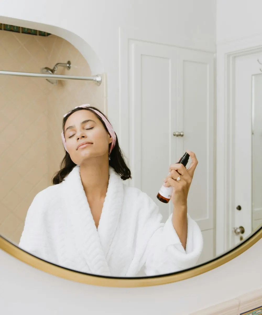 Woman in a white robe enjoying her skincare routine at the mirror