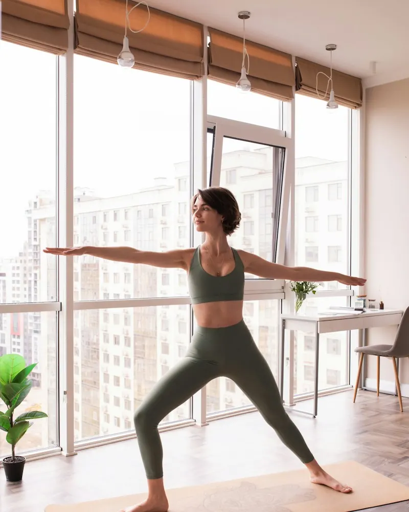 Woman in sage leggings practicing yoga in a bright room