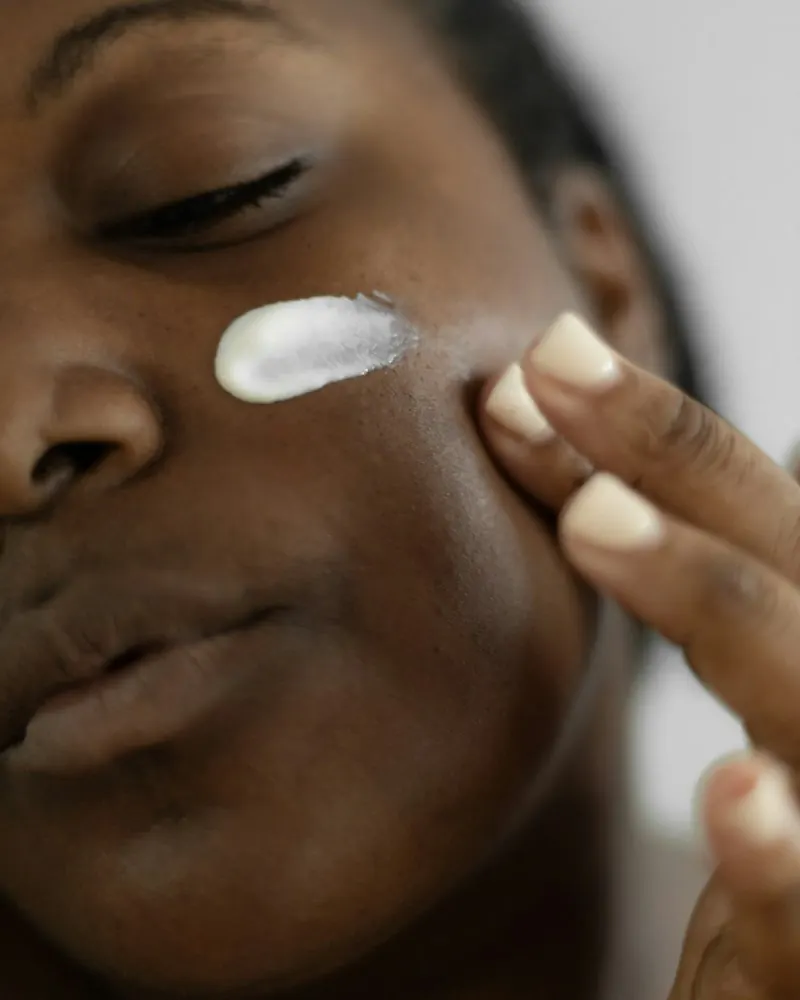 Close-up of a woman applying moisturizer to her cheek